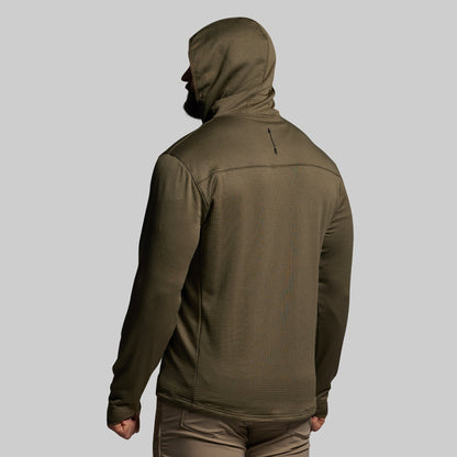 Person wearing a green hooded mid layer on a gray background
