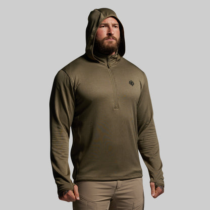Man wearing a green hooded mid layer on a gray background