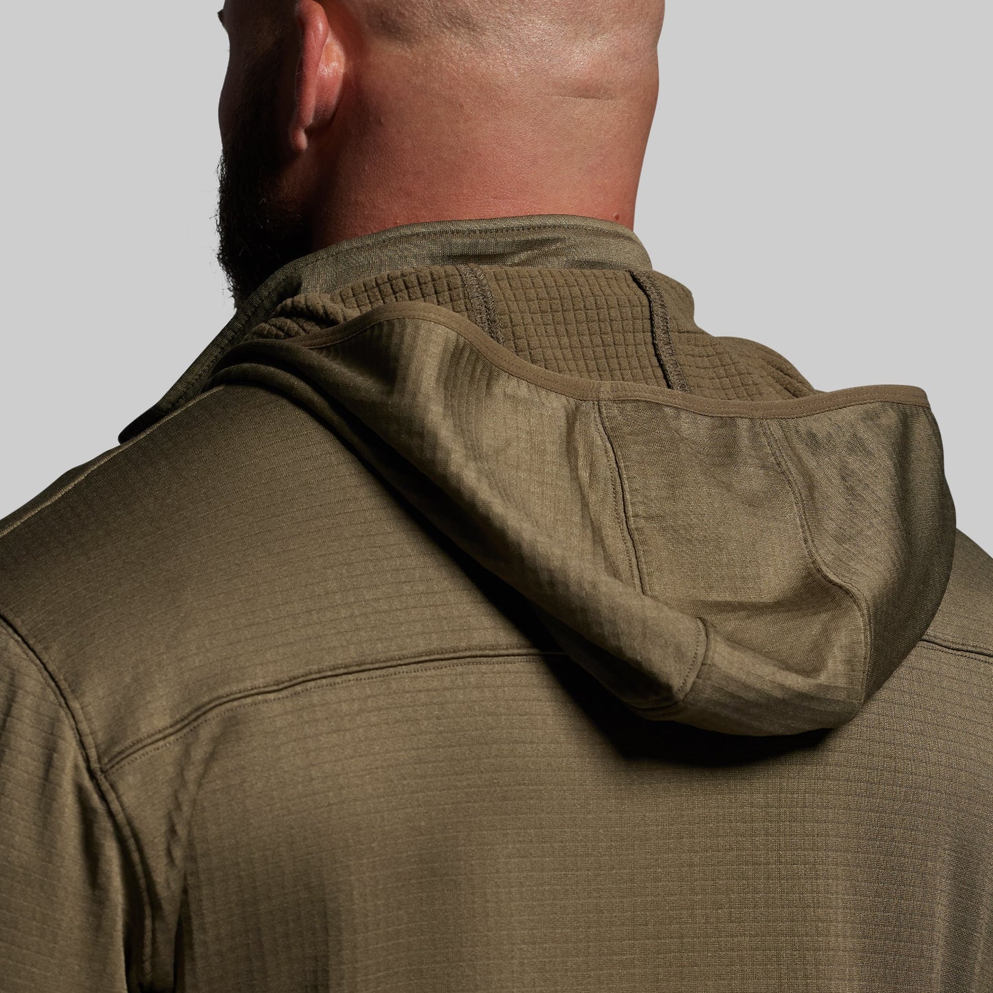 Close-up of a person wearing a green hoodie on a plain background