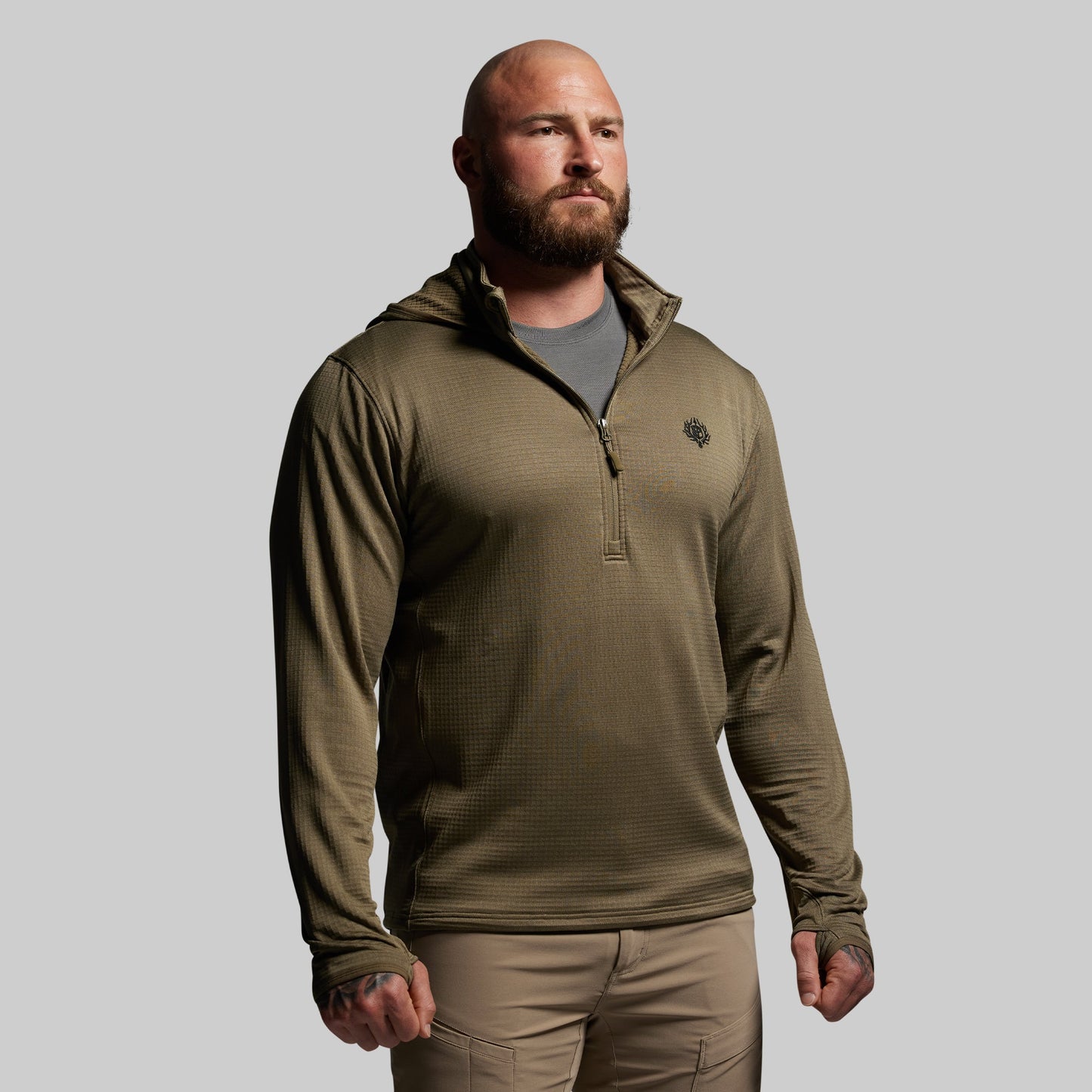 Man wearing a green pullover with a logo on a gray background