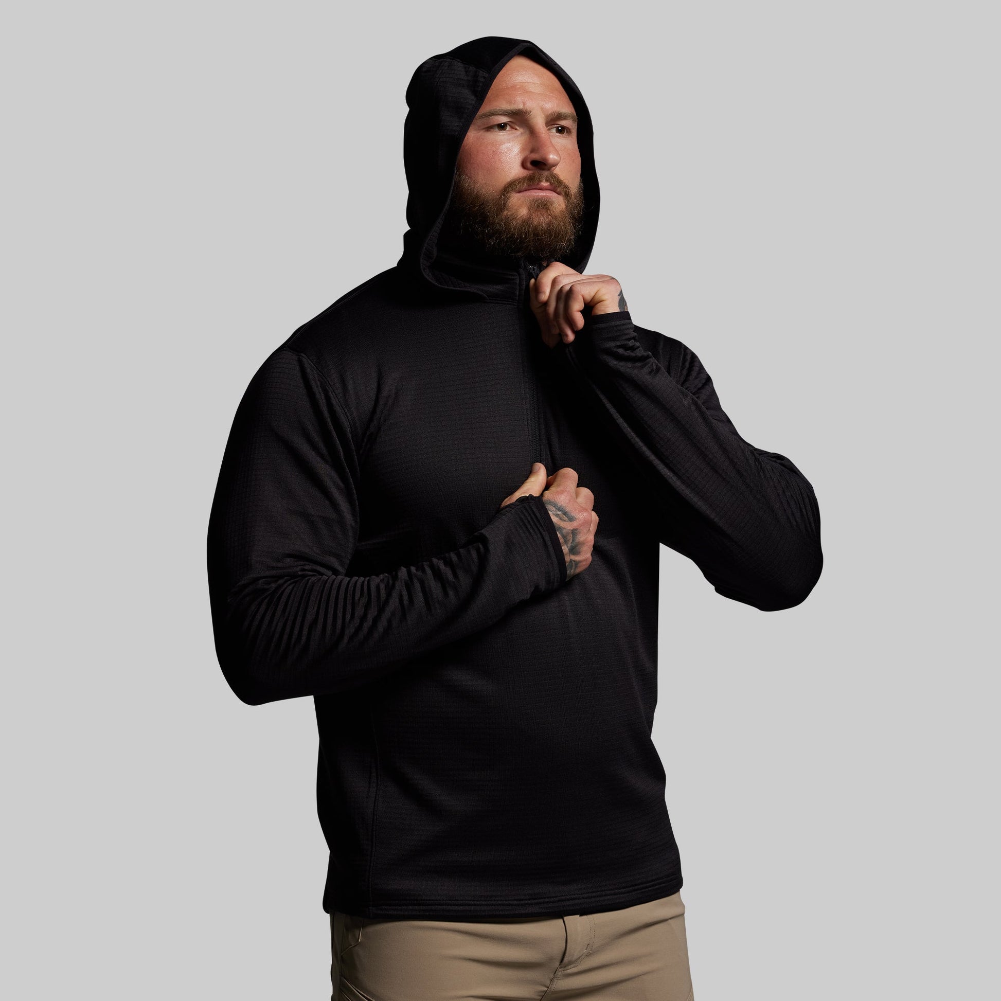 Man wearing a black hoodie against a gray background