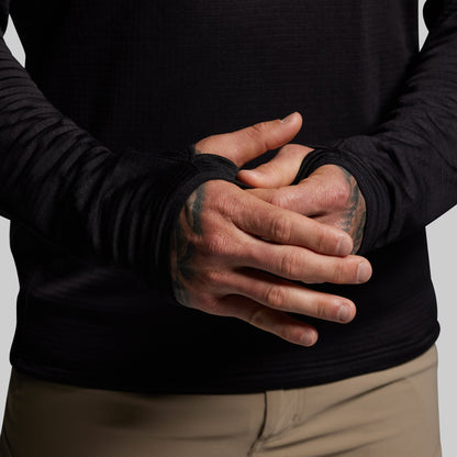 Person wearing a black quarter zip hoodie with thumbholes on a plain background
