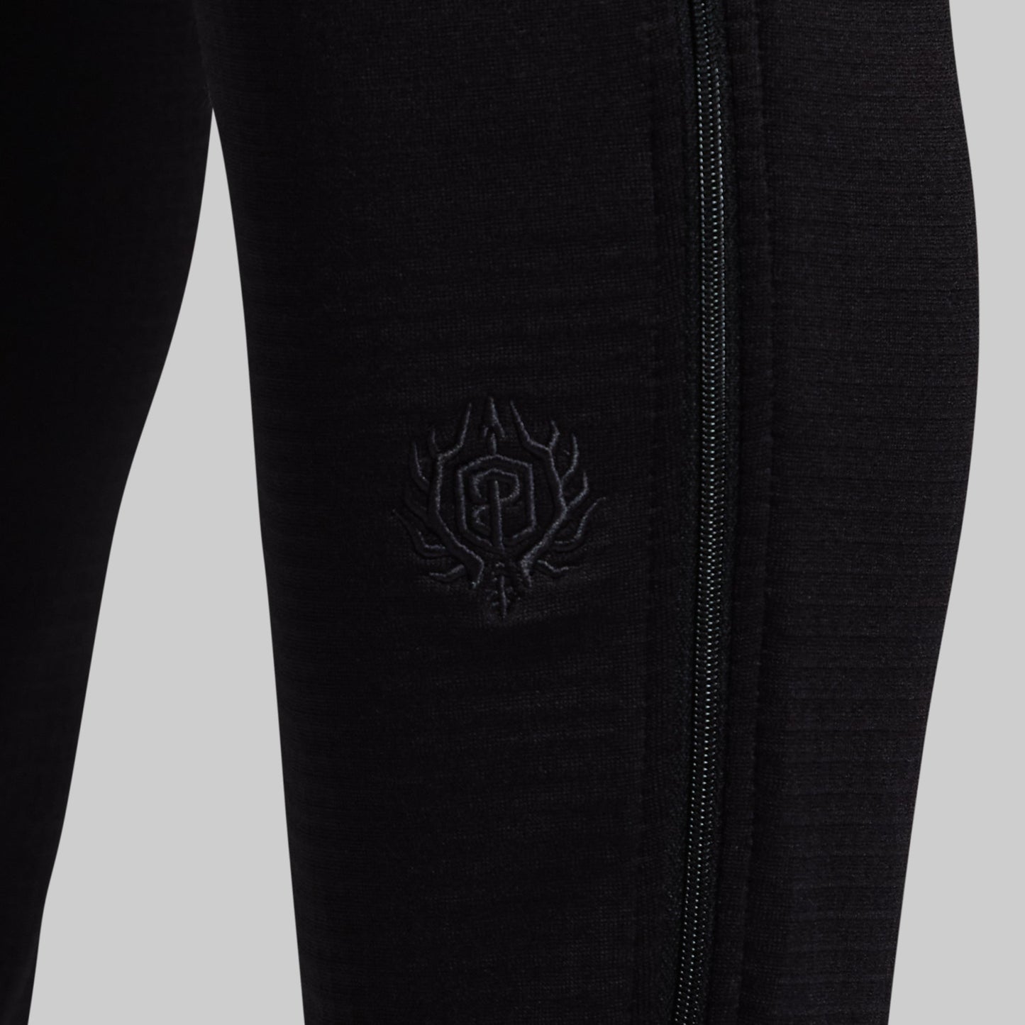 Black pants with a logo against a light gray background
