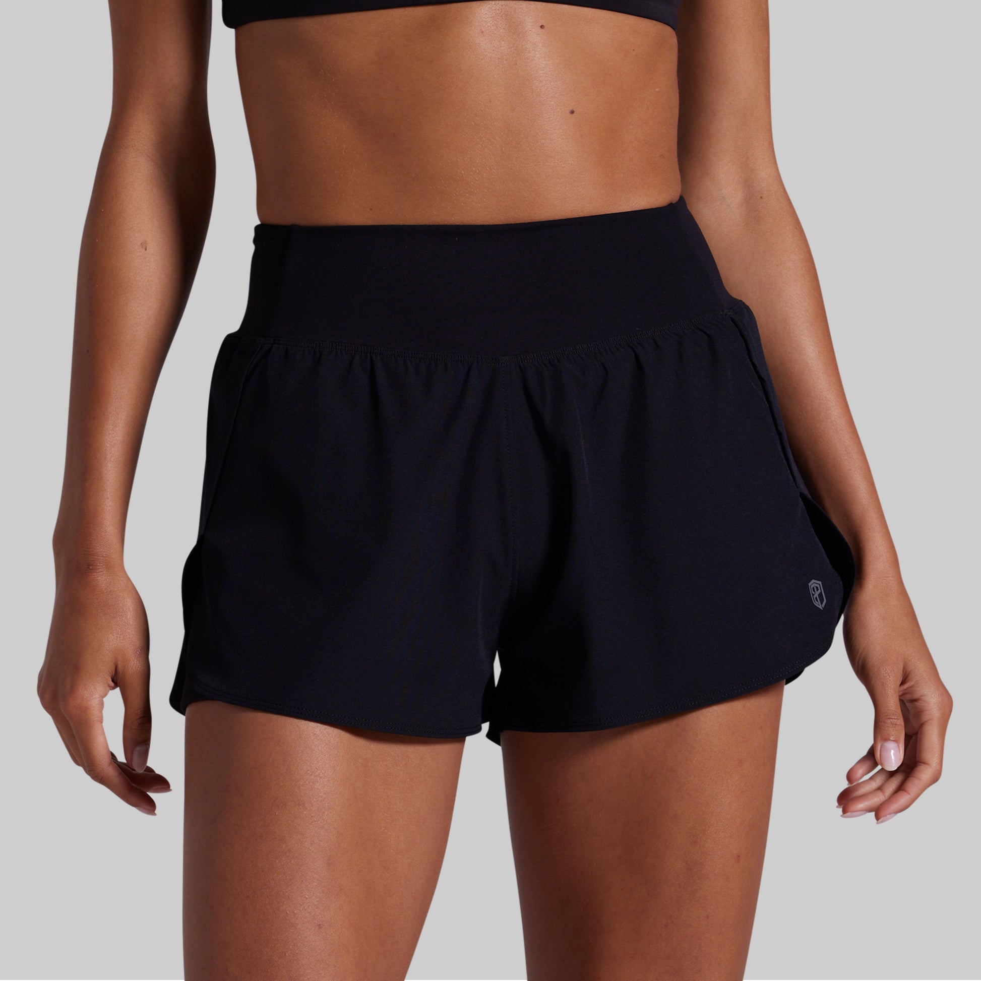 Black athletic shorts worn by a person on a gray background