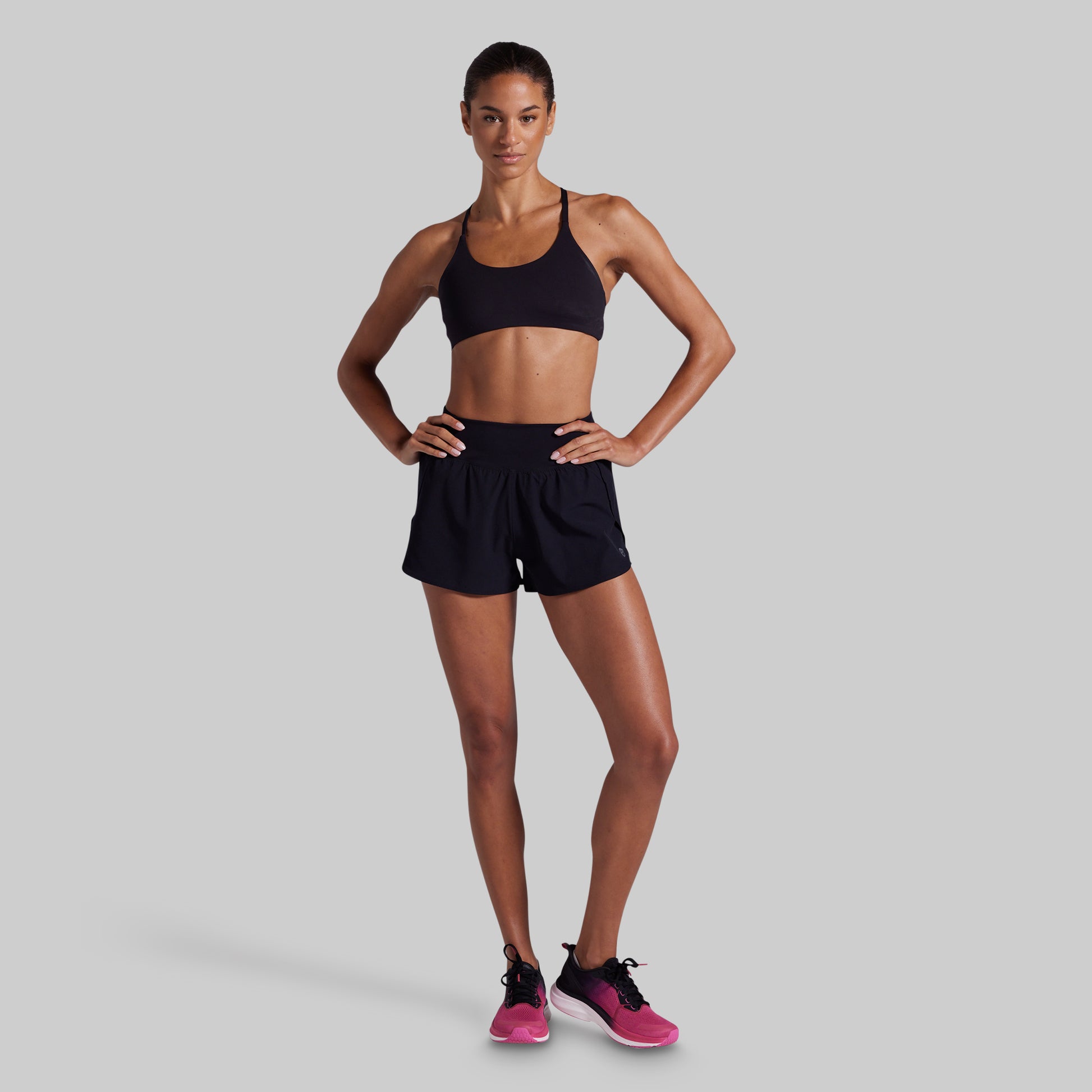 Woman wearing a black sports bra and shorts on a gray background