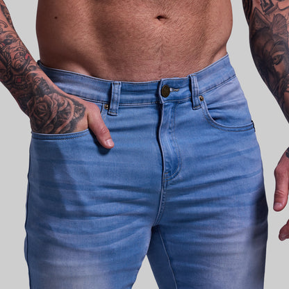 Person wearing blue jeans with a plain background