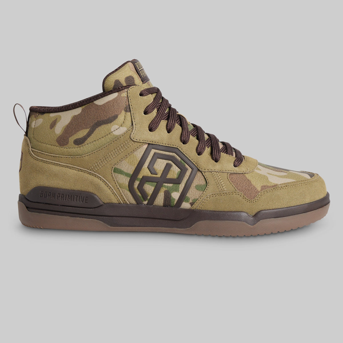 A mid-top sneaker from the brand BORN PRIMITIVE, featuring a tan and brown camouflage pattern with dark brown laces, a dark brown geometric logo on the side, and a brown outsole, shown against a solid gray background.