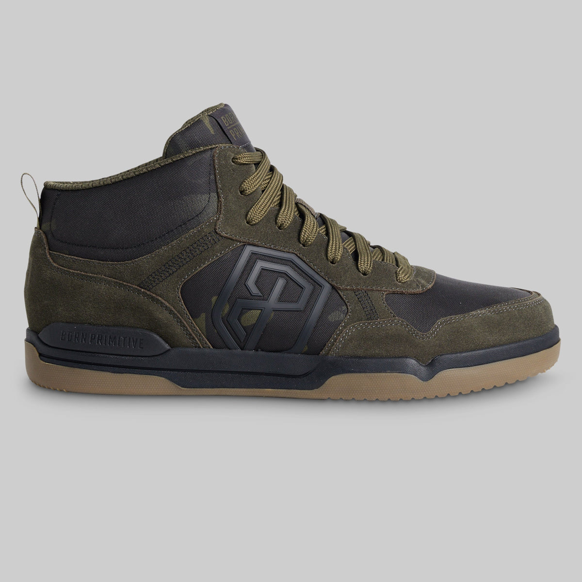 A mid-top athletic sneaker in olive green suede and black synthetic panels, featuring a tan gum sole, shown from a side profile view on a solid gray background.
