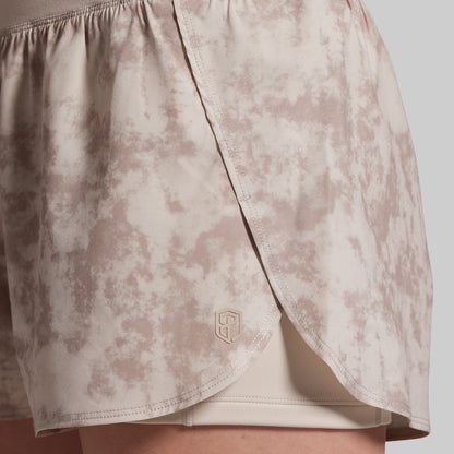 Beige patterned shorts with a brand logo on a light gray background