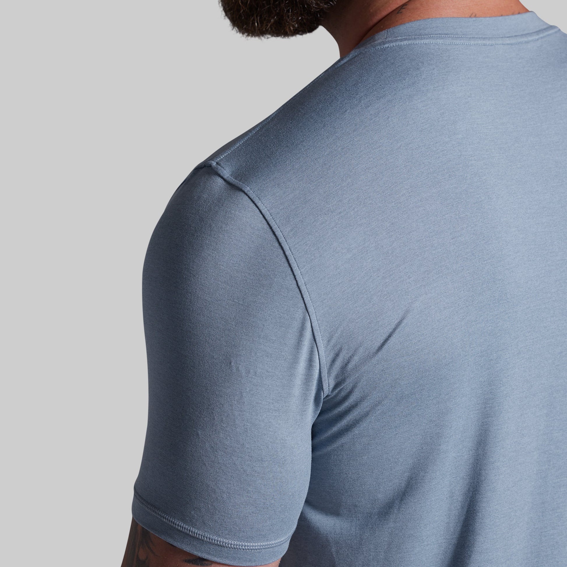 Person wearing a light blue t-shirt on a gray background