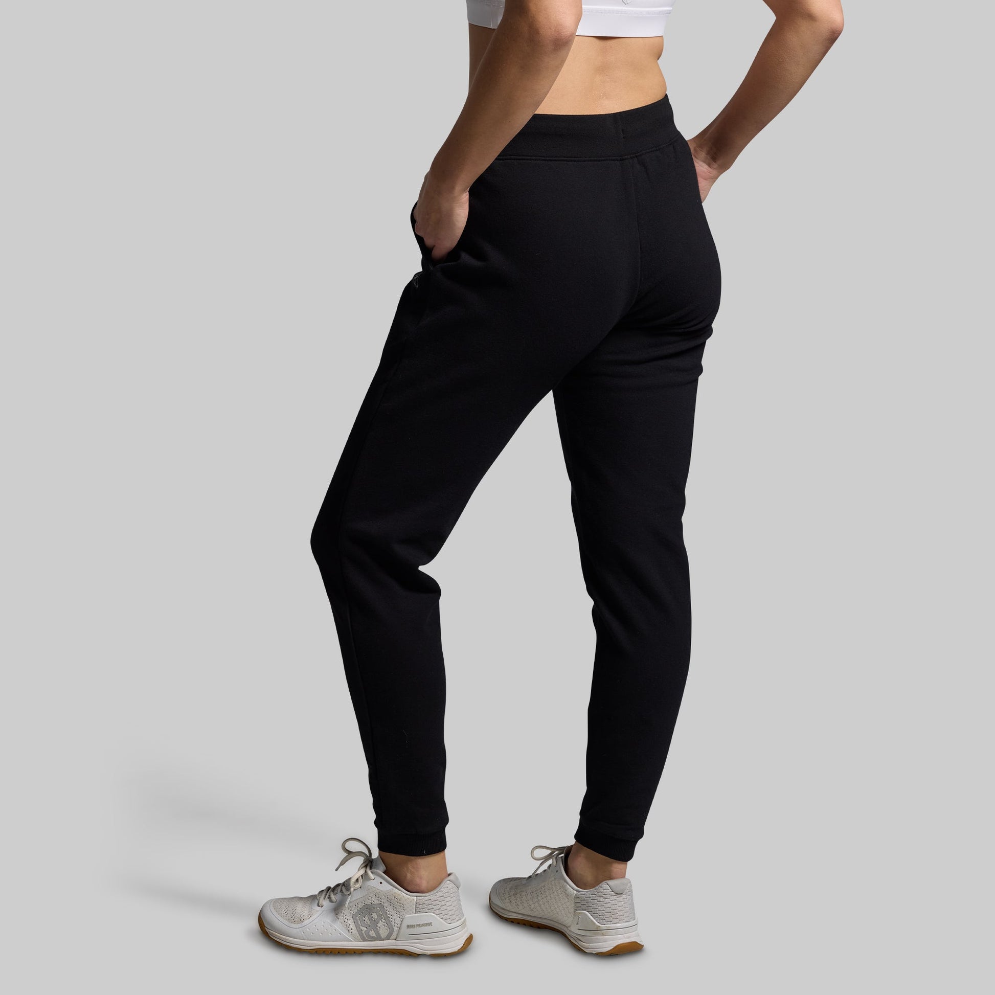Person wearing black jogger pants on a gray background