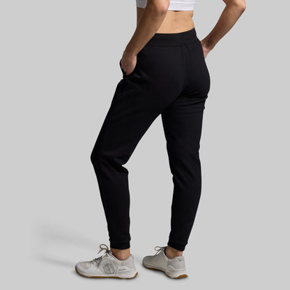 Person wearing black jogger pants on a gray background