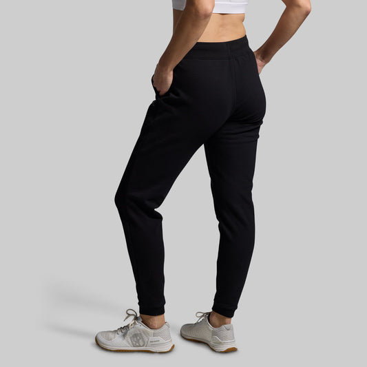 Person wearing black jogger pants on a gray background