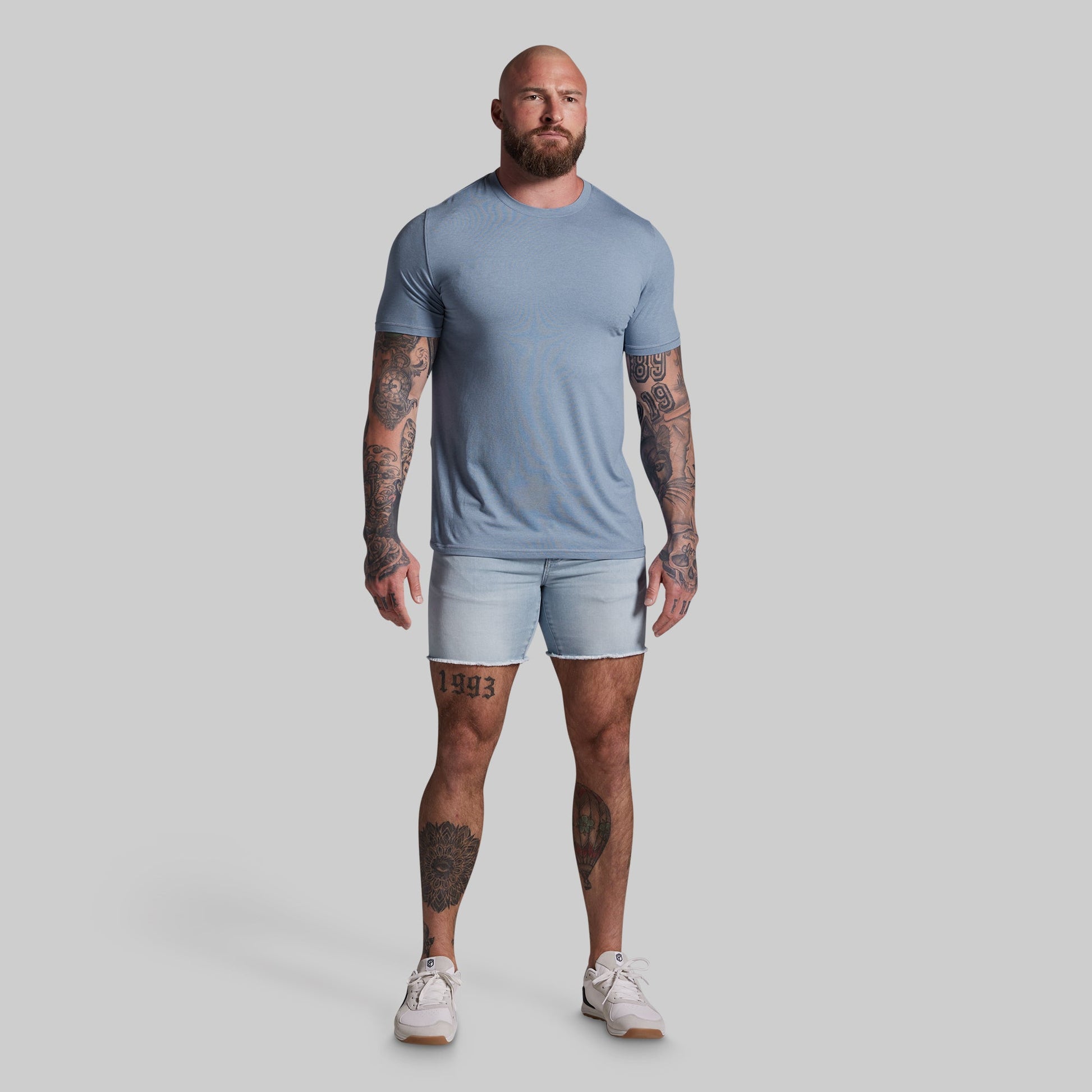 Man wearing a light blue t-shirt and shorts on a gray background