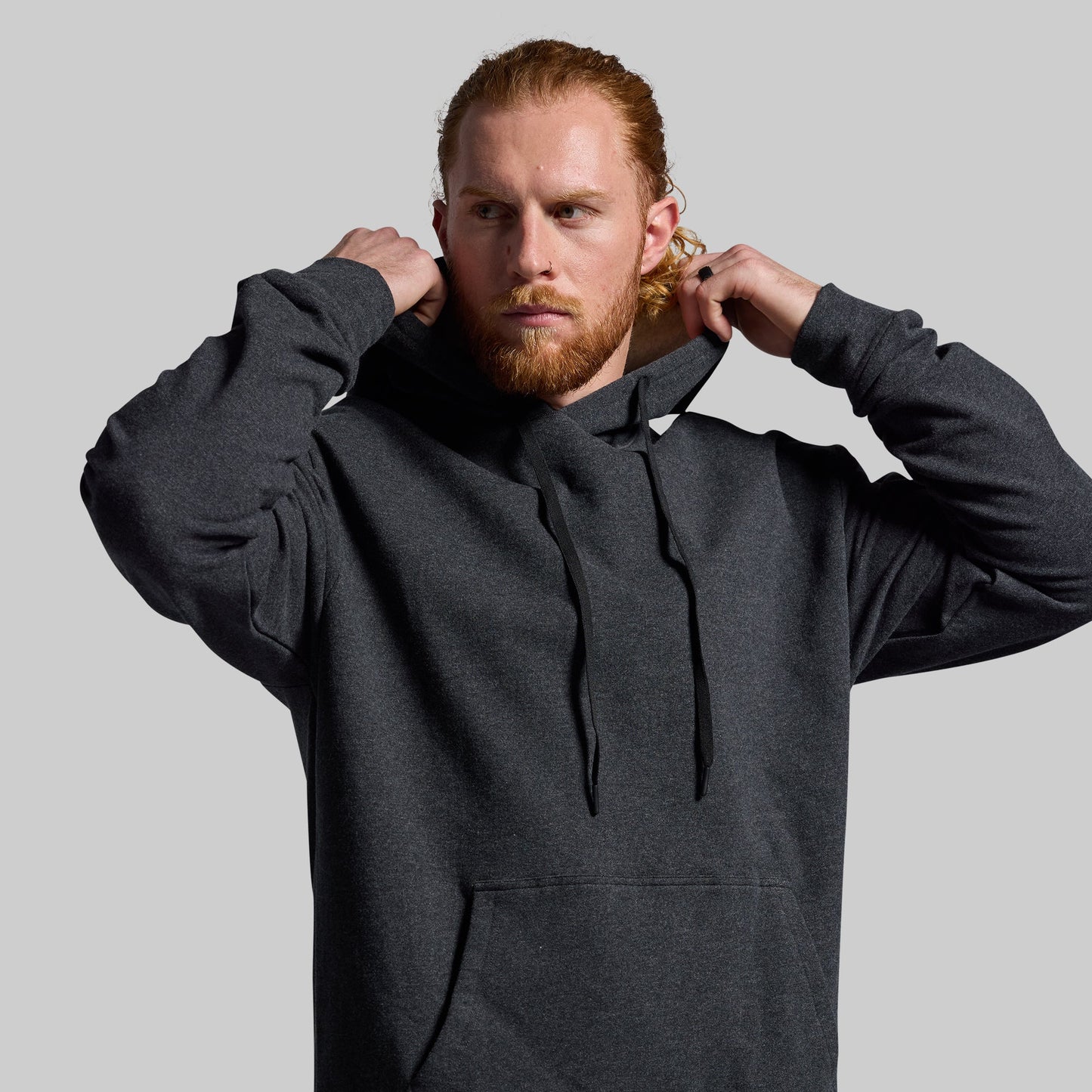 Man wearing a dark gray hoodie against a plain background