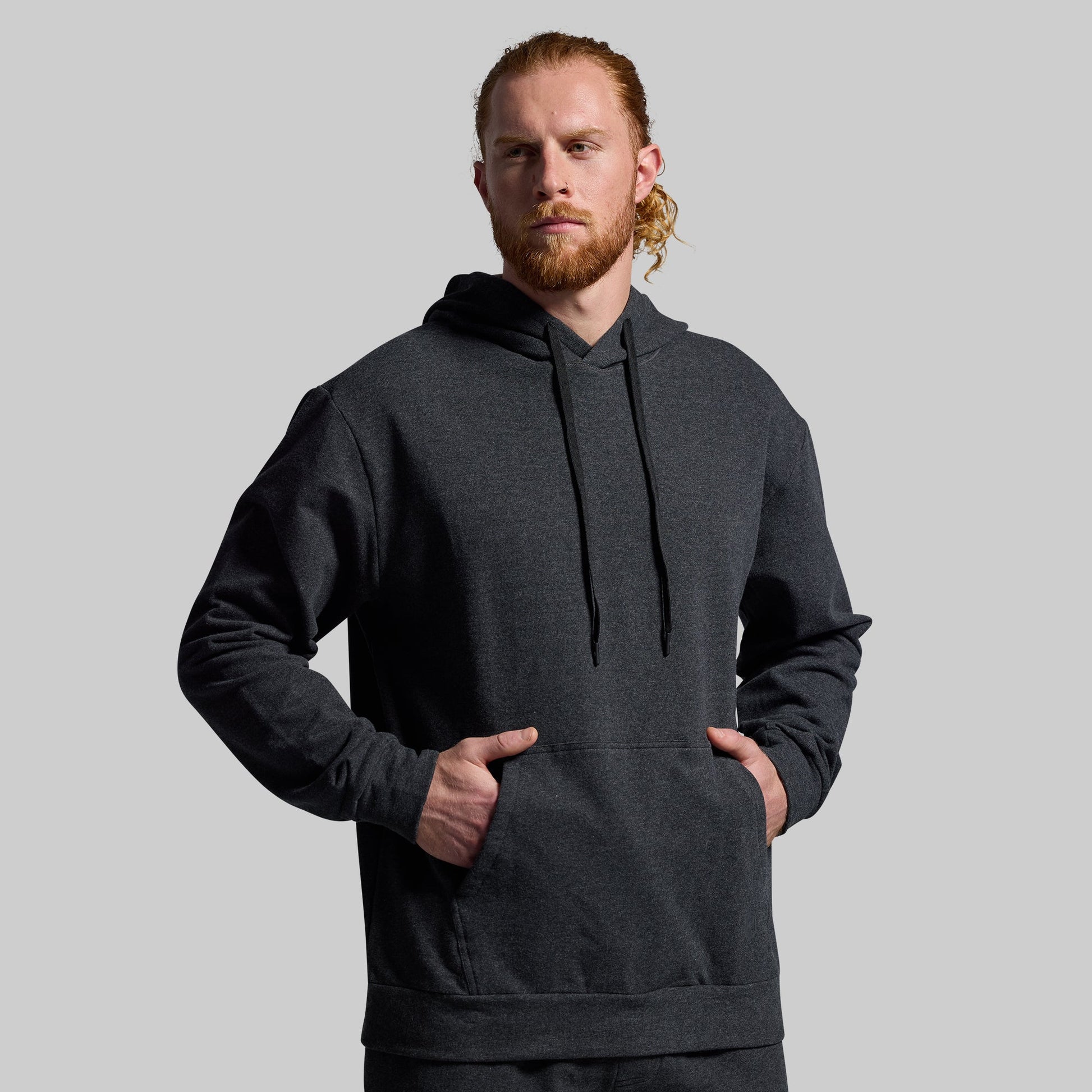 Man wearing a dark gray hoodie against a plain background
