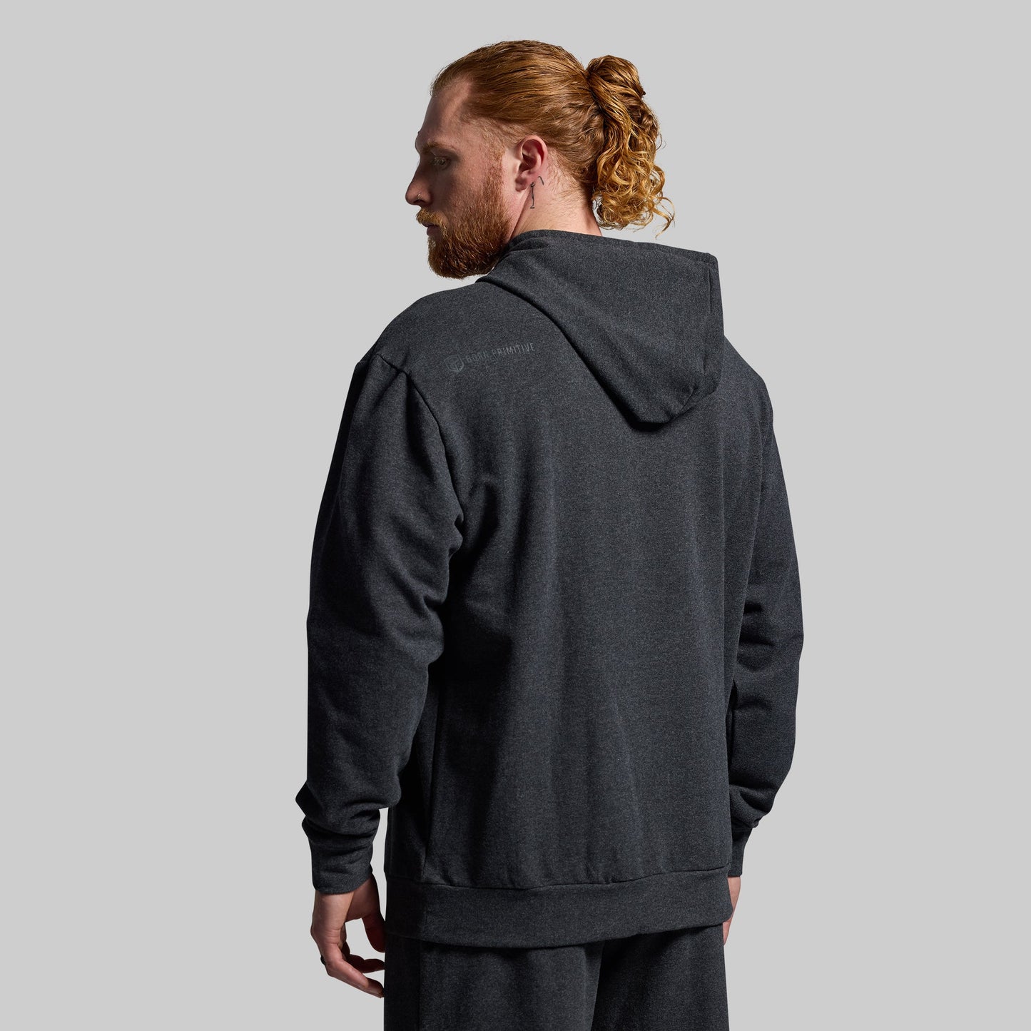 Man wearing a dark gray hoodie from behind on a light gray background