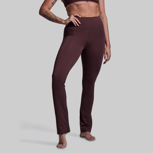 Person wearing brown yoga pants on a plain background
