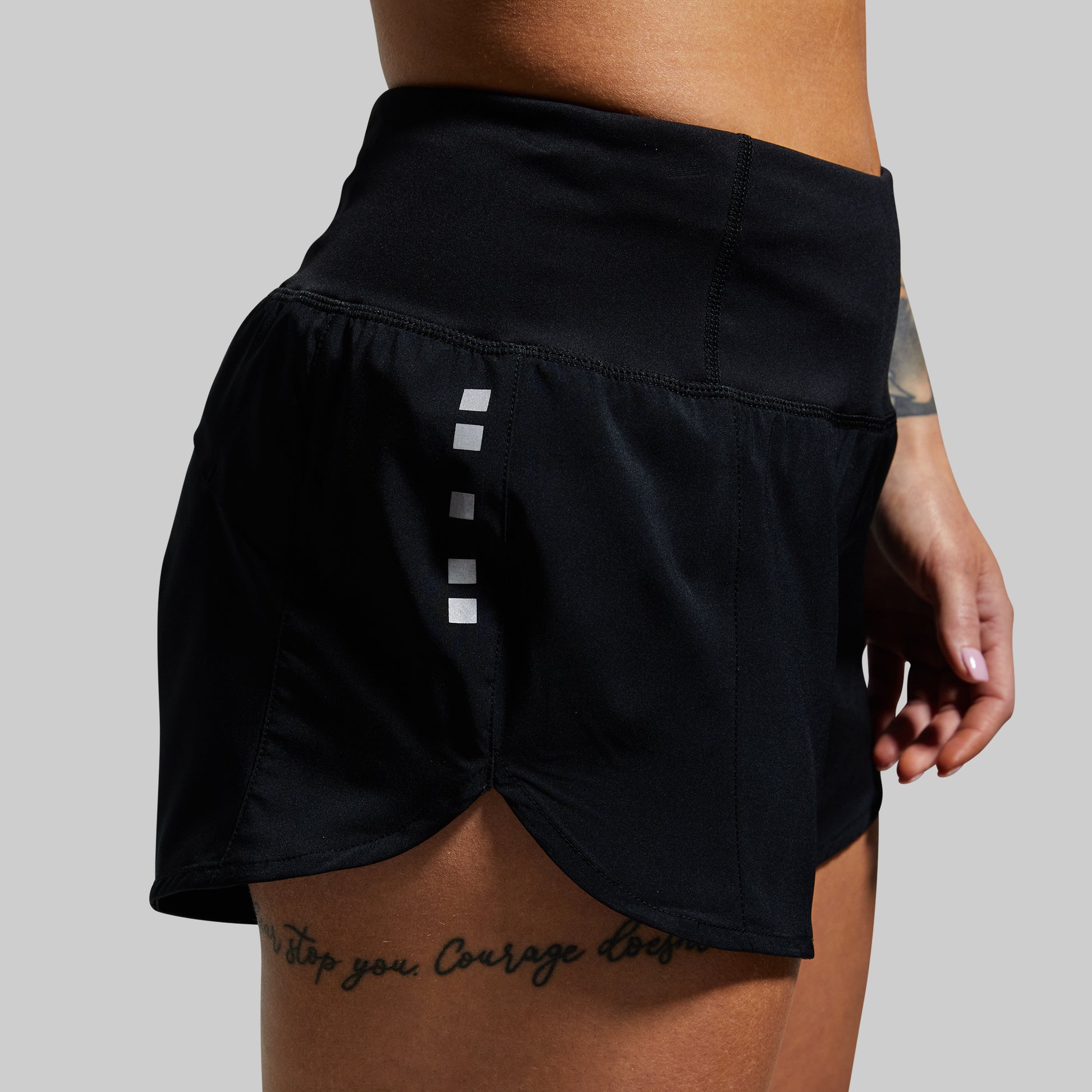 Black athletic shorts with a reflective stripe on a gray background