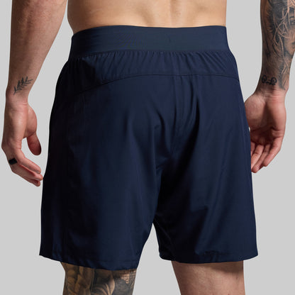 Navy blue athletic shorts worn by a person on a gray background