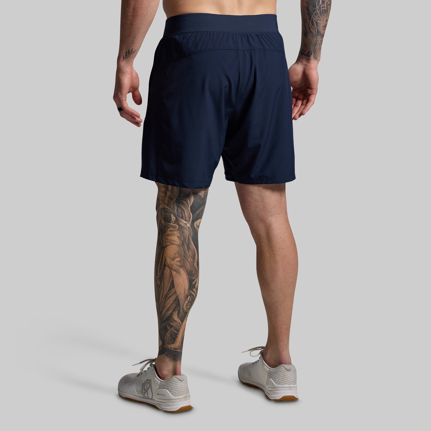 Person wearing navy shorts on a gray background