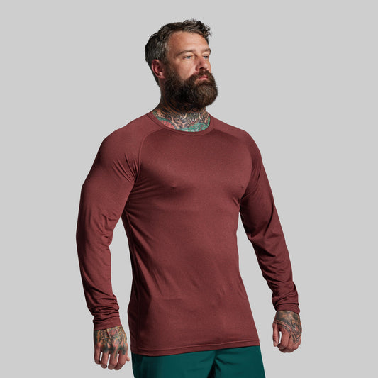 Man wearing a maroon long-sleeve shirt against a gray background