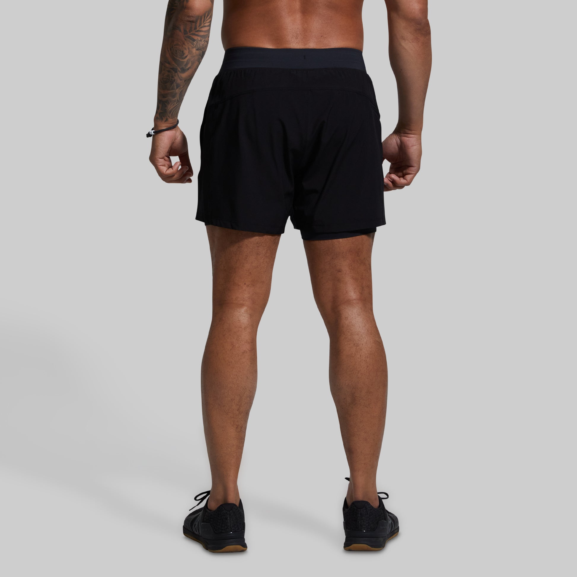 Person wearing black athletic shorts on a gray background