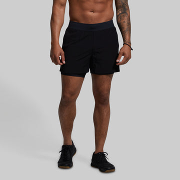 Person wearing black shorts on a gray background