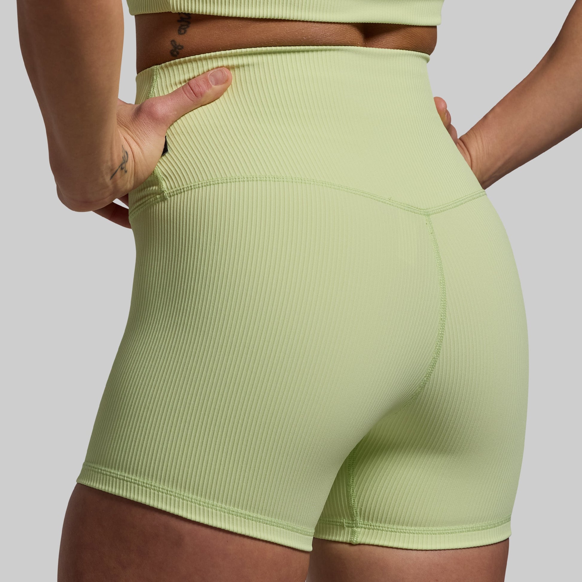 A pair of light green high-waisted compression shorts with a ribbed texture and a slightly longer inseam.
