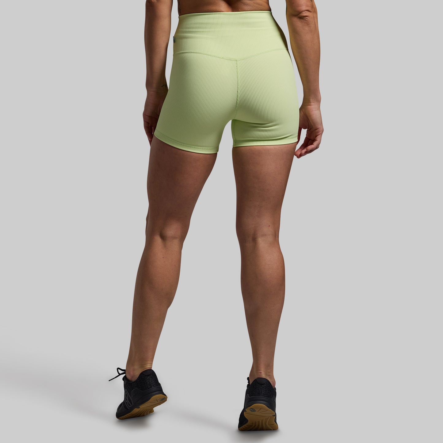 Person wearing light green athletic shorts on a gray background
