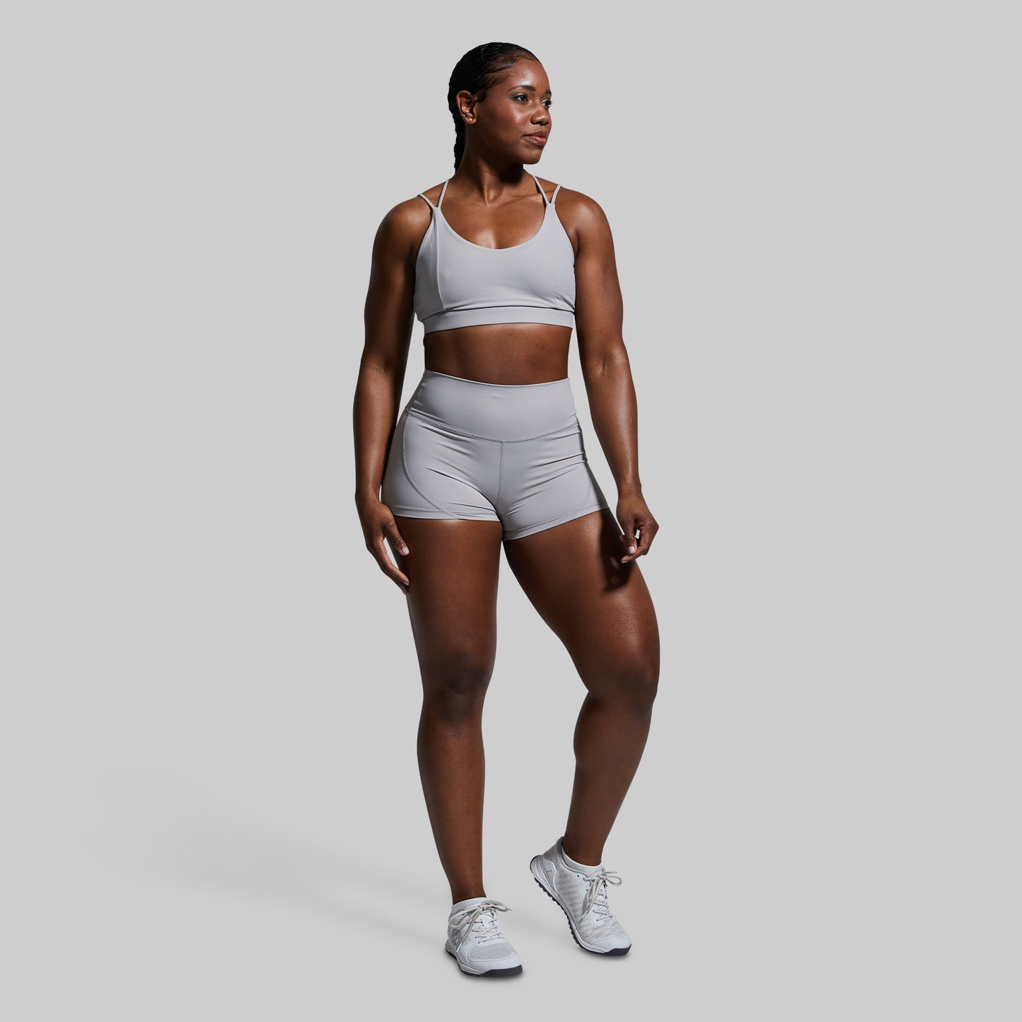 Woman wearing a gray athletic outfit on a plain background