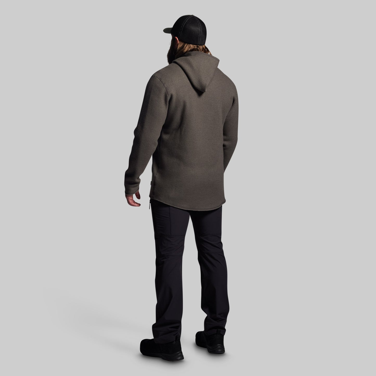 Person wearing a gray hoodie and black pants on a light gray background