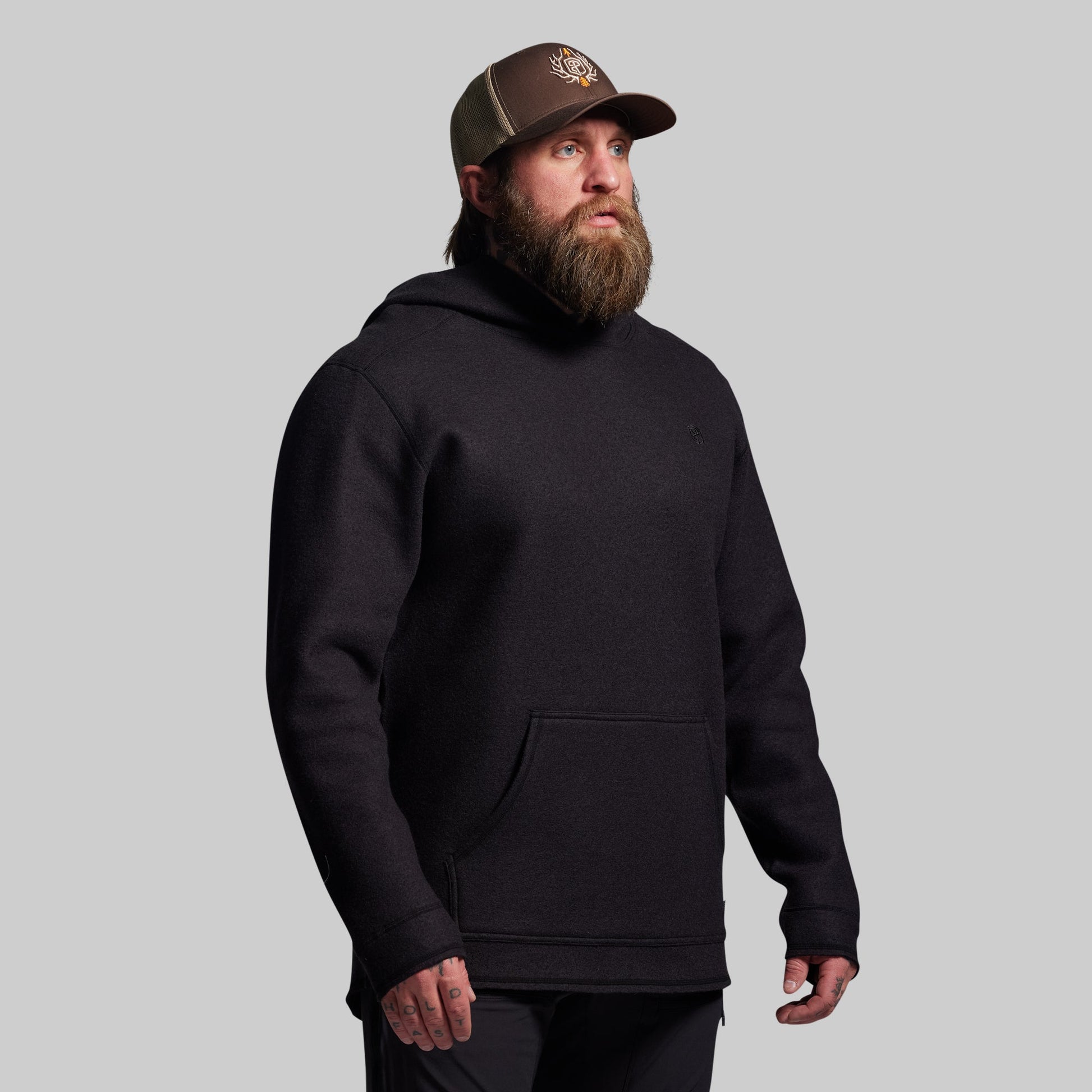 Man wearing a black hoodie and brown cap on a gray background