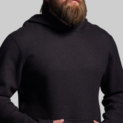 Person wearing a black hoodie against a gray background