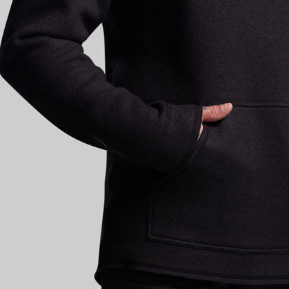 Person wearing a black hoodie with a plain background