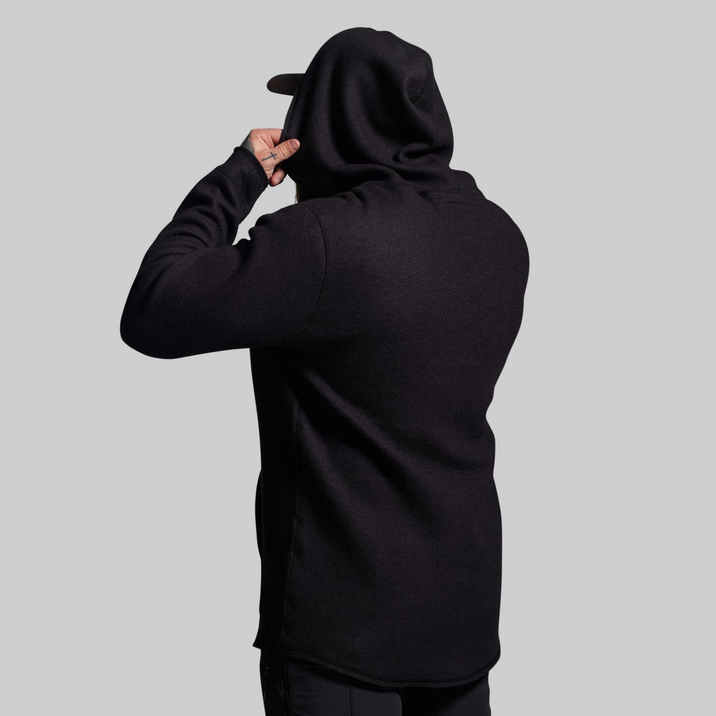 Person wearing a black hoodie with a plain background