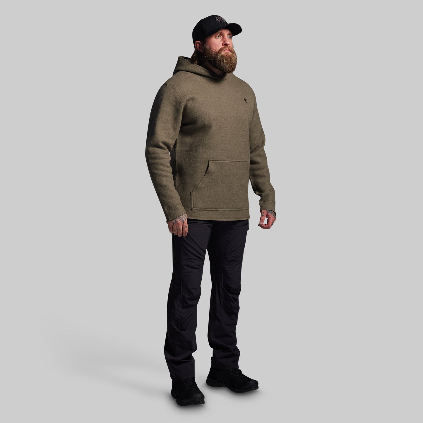 Man wearing a green hoodie and black pants on a gray background