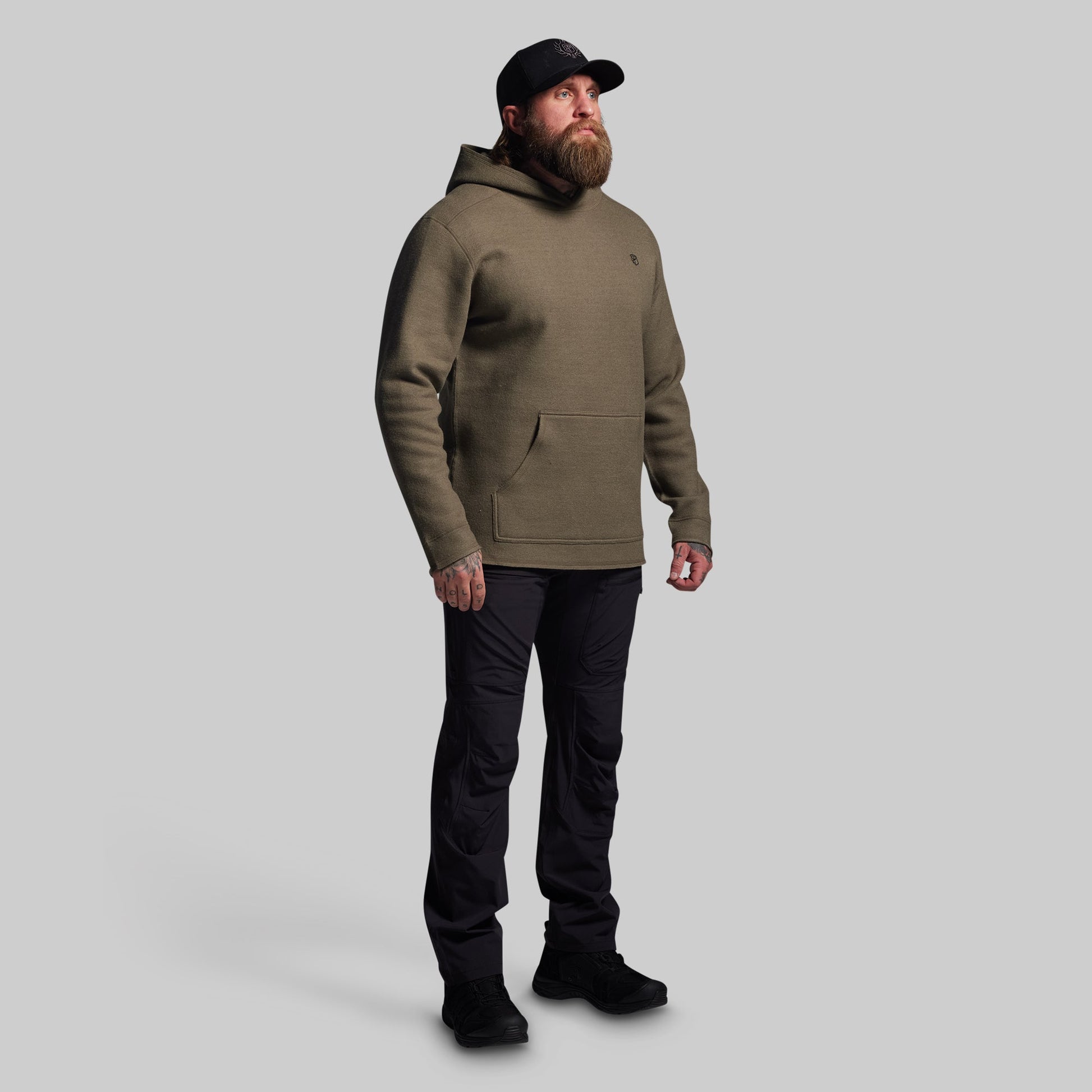 Man wearing a green hoodie and black pants on a gray background