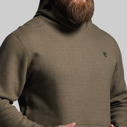 Person wearing a green hoodie with a small logo on the chest against a plain background