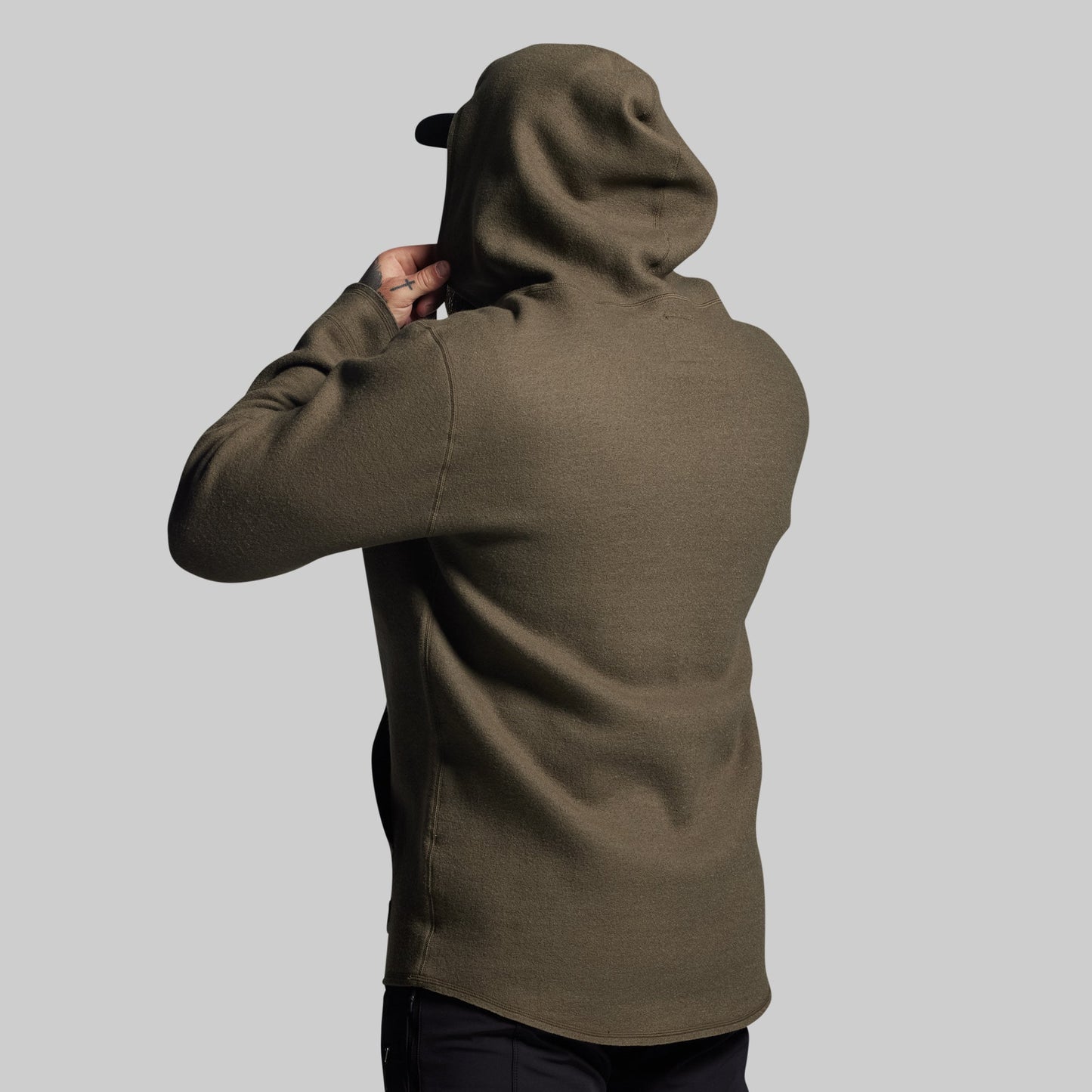 Person wearing a green hoodie from behind on a light gray background