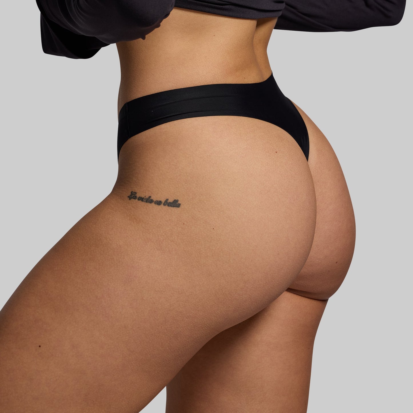 Person wearing black underwear with a plain background