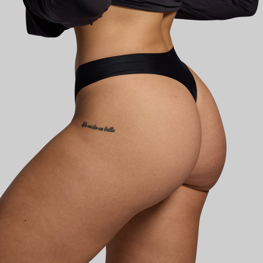 Person wearing black underwear with a plain background