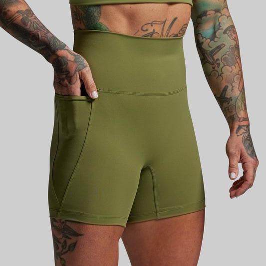 Person wearing green athletic shorts with a plain background