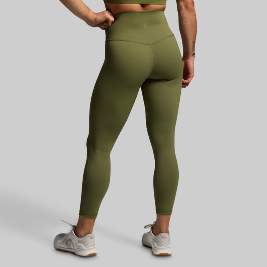 Person wearing olive green leggings on a gray background