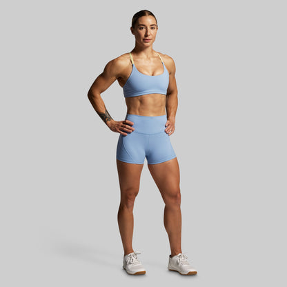 Woman wearing a light blue sports bra and shorts set on a gray background