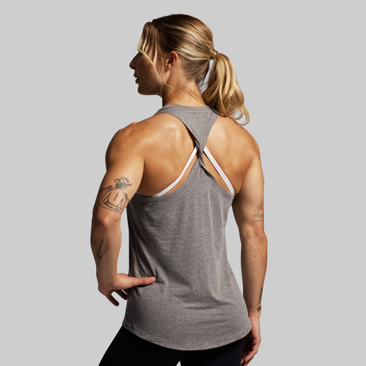Woman wearing a gray tank top with thin straps on a plain background