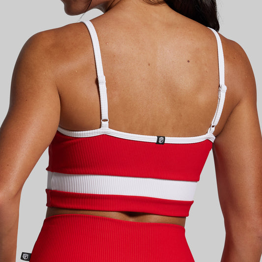 Red sports bra and shorts set with white straps on a neutral background