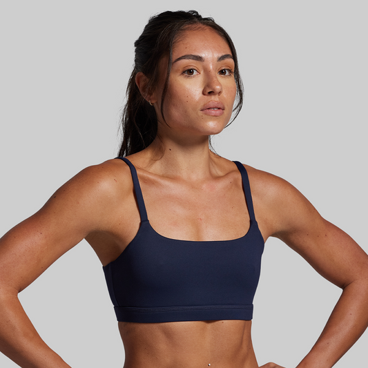 Woman wearing a navy blue sports bra against a gray background