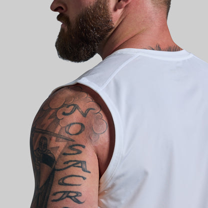 Man wearing a white tank top with visible tattoos on his arm against a plain background