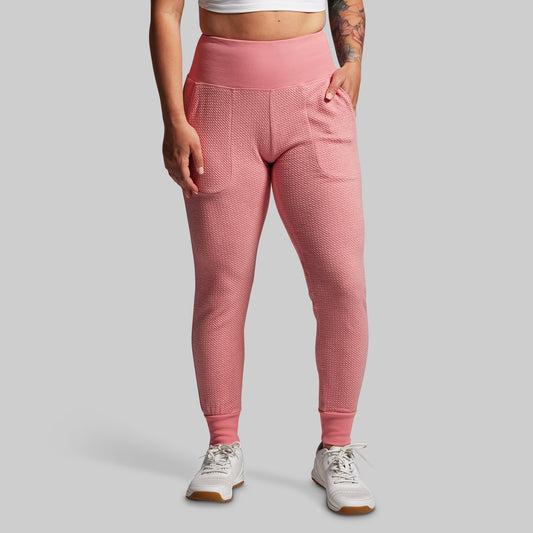 Person wearing pink textured joggers on a gray background